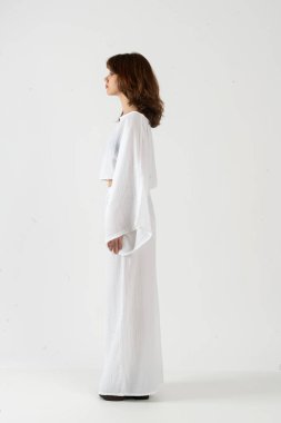 Geniş kollu, geniş kollu, geniş pantolonlu, minimalist stüdyo görünümlü bir kadın profili..