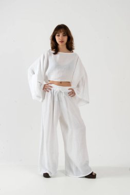 Kendine güvenen genç bir kadın geniş kollu bluz ve geniş pantolonlu poz veriyor..