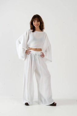 Geniş kollu, gevşek bluz bluz bluz ve geniş bacak pantolonuyla gülümseyen mutlu genç kadın..