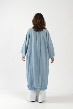 Uzun açık mavi kimonolu, püsküllü ve geniş pantolonlu bir kadın..