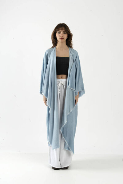 Молодая женщина в черном топе, белых широких брюках и длинном светло-голубом кимоно с краями.