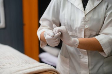 Female cosmetologist beautician doctor wear latex medical gloves, hands close up, beauty industry indoors