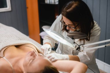 Armpit electrolysis in beauty clinic close up, beautician make professional hair removal for female client
