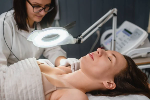 Armpit electrolysis in beauty clinic close up, beautician make professional hair removal for female client