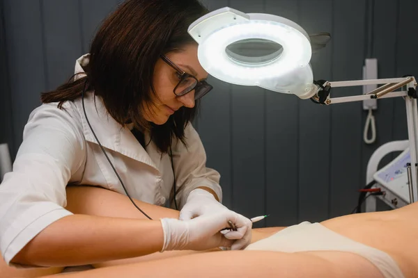 Cosmetologist work on bikini zone to remove hair, electrolysis professional procedure in beauty spa salon close up
