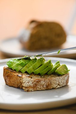 Close-up of delicious avocado slices on toast. Avocado sandwich on a white plate.