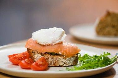 Sandwich with poached egg on a white plate, close-up. Breakfast concept.