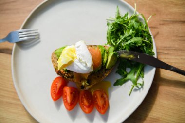 Avocado toast with poached egg on a wooden board. Breakfast concept.