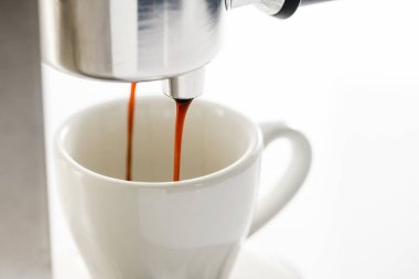 Espresso makinesi seramik fincana taze kahve dolduruyor, yakın plan..