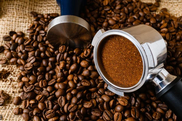 stock image Close up macro fine grinding coffee for espresso in metal holder for carob maker with tamper, holder and beans, natural background