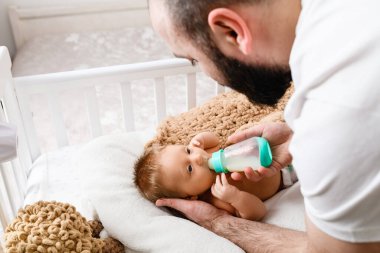 Baba, uykulu bebeği plastik şişeden bebek sütü formülüyle besle, gündüz uykusuna hazırlan, baba baba baba aile bakımı.