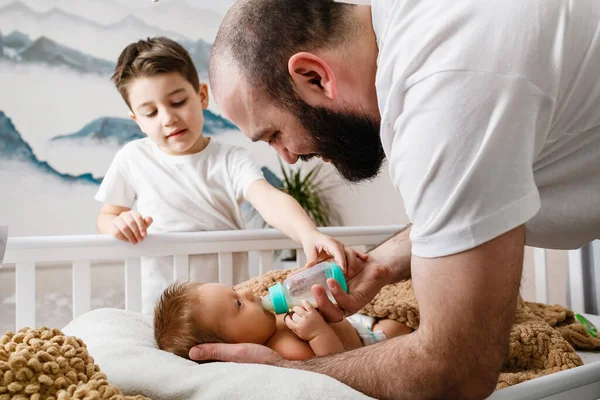 Padre Hermano Mayor Alimentan Recién Nacido Con Fórmula Bebé Cuna — Foto de Stock