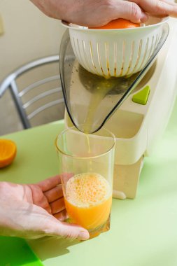 Evde sağlıklı yiyecekler. Kadın mutfakta taze portakal suyu hazırlıyor..