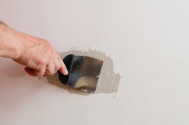 Alçıpandaki delikleri onarıyorum. Tamircinin biri duvardaki alçıpanı tamir ediyor..