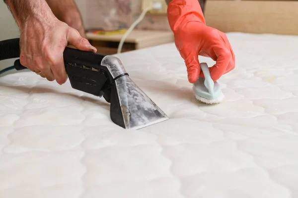 Cleaning the mattress with a washing vacuum cleaner. Close-up.