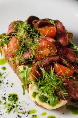 Sulu etli, domatesli, otlu, peynirli, soslu beyaz tabak. Yakın plan..