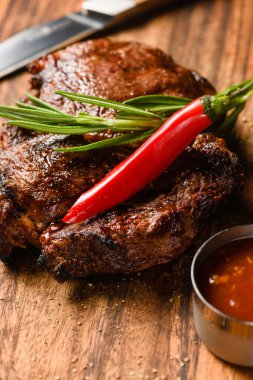 Tahta kesme tahtasının üzerinde nefis bir biftek. Yakın çekim, üst görüş. Koyu arkaplan.