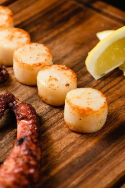 Ahşap kesme tahtasının üzerinde çeşitli ızgara deniz ürünleri, koyu arka plan. Yukarıdan görüntüle.