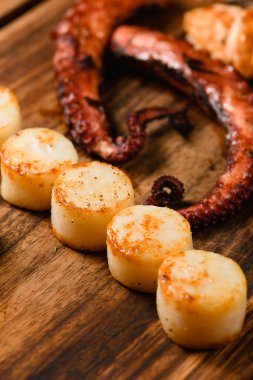 Ahşap kesme tahtasının üzerinde çeşitli ızgara deniz ürünleri, koyu arka plan. Yukarıdan görüntüle.