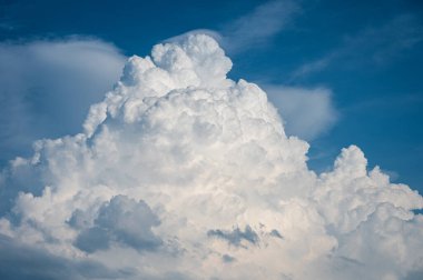 Mavi gökyüzünde dağ şeklinde kocaman kabarık bir bulut. Kümülüs ve sirrus bulutlarıyla güzel gökyüzü arkaplanı.