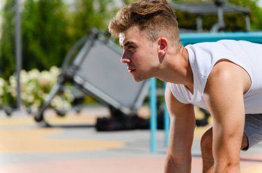 Spor arka planında çömelmiş bir pozisyonda koşan bir adamı vurmuşlar. Yan görüş. Koşan bir adamın profili.