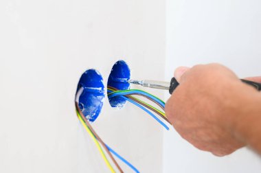 Bir elektrikçi duvara bir soket takar. Yakın plan..