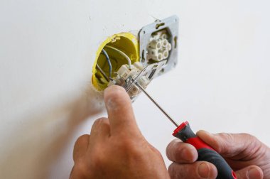 Bir elektrikçi duvara bir soket takar. Yakın plan..