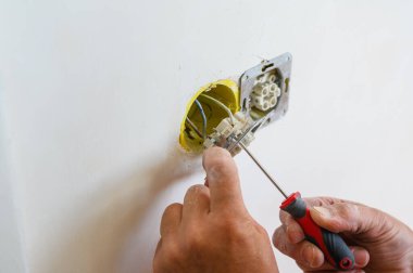 Bir elektrikçi duvara bir soket takar. Yakın plan..
