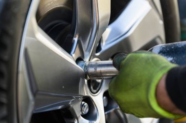 Araba tamircisi açık havada lastik değiştiriyor.