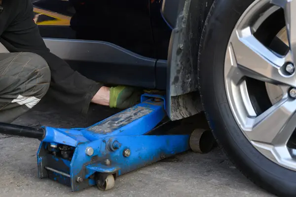 Araba tamircisi açık havada lastik değiştiriyor.