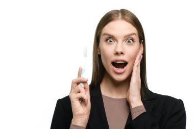 Kız elinde bir diş fırçası tutarak ve diş telleriyle güzel düz dişler göstererek geniş bir şekilde gülümsüyor..