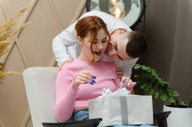 Bir erkek bir kıza hediye verir. Bir adam bir kıza arkadan sarılıyor. Kız sandalyede oturuyor..