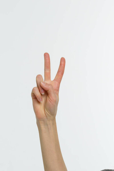 Female hand showing peace sign or victory sign on white background. Close-up.