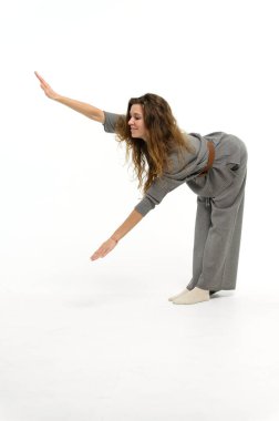 Genç ve çekici bir kadın beyaz bir arka planda vücut büküyor..