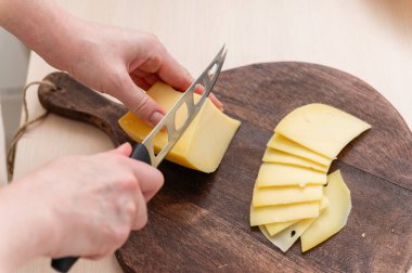 Bir kadın peyniri ince dilimlere ayırıyor. Yakın plan..