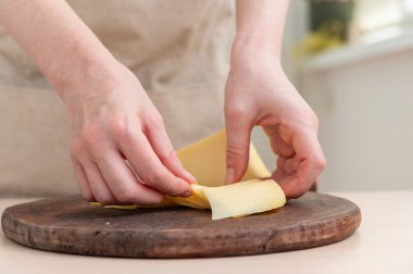 Bir kadın peyniri ince dilimlere ayırıyor. Yakın plan..