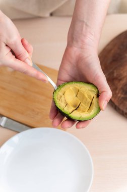 Mutfakta taze avokado kesen kadın ellerinin yakın çekimi..
