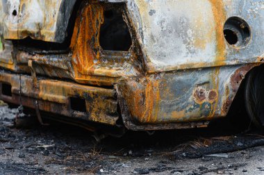 Yanmış araba enkazı doğada yol kenarında terk edilmiş. Yanmış bir arabanın bagajına yakın çekim..