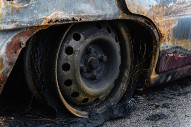 Yakılmış ve yok edilmiş bir araba. Yanmış tekerleğin yakın çekimi. Kablo kablosuyla yanmış siyah lastik..