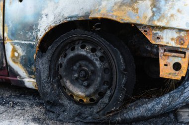 Yakılmış ve yok edilmiş bir araba. Yanmış tekerleğin yakın çekimi. Kablo kablosuyla yanmış siyah lastik..