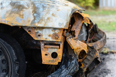 Yakılmış ve yok edilmiş bir araba. Yanmış tekerleğin yakın çekimi. Kablo kablosuyla yanmış siyah lastik..