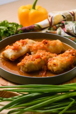 Geleneksel doldurulmuş lahana ruloları soğan ve havuçla birlikte zengin domates sosunda haşlandı. Sıcak, sulu bir dürüm ev yapımı bir tabakta..