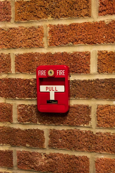 Manual fire alarm activation pull station on wall - signage reading: FIRE FIRE and PULL