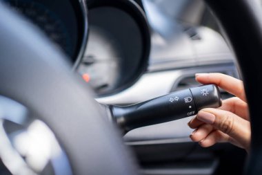 Farların kontrol düğmesini açan elin yakın çekimi.