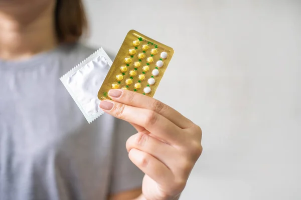 Ontraceptive means: Woman hand holding contraceptive pills and condom. Protection, safe sex. Contraception, concept birth control.
