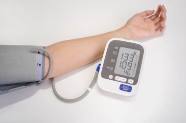 Kadın kan basıncını elektronik dijital tonometreyle ölçüyor, kadın eli yakın. Arteriyel hipotansiyon ve kardiyoloji konsepti