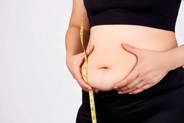 白い背景に測定テープで過剰な腹の脂肪を保持脂肪女性 腹部の筋肉の引き締め 肥満の概念 — ストック写真