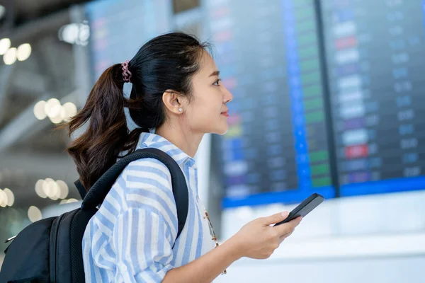 Asian female traveler checking flights at international airport on weekend trip