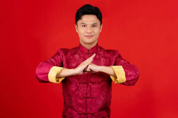 Happy Chinese new year. Handsome Asian man gesture of congratulation isolated on red background. Celebration concept.