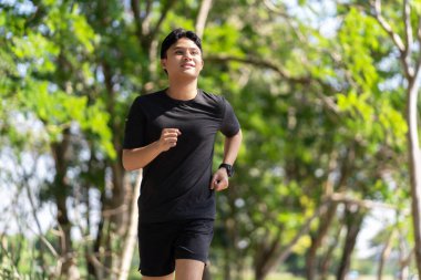 Active healthy Asian man jogging at the park in the morning. Healthy lifestyle, workout and wellness concept